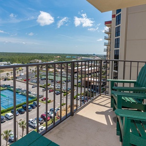 The master balcony features two green Adirondack chairs overlooking a view of tennis courts and lush greenery in the distance