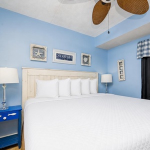 This inviting bedroom features a comfortable bed, cheerful blue walls, and charming coastal decor for a relaxing stay