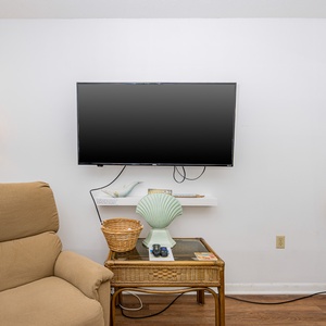 This cozy living area features a comfortable chair, a TV for entertainment, and charming coastal decor elements