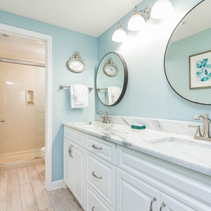 Refresh in this bright master bath featuring dual sinks, elegant marbled countertops, and spacious walk-in shower