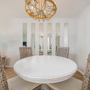 Dine at the round table surrounded by stylish chairs, complemented by a unique chandelier and mirrored accents