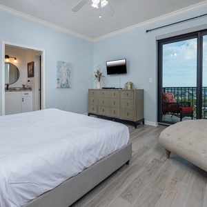 Tranquil master suite featuring a plush king bed, stylish decor, and access to a balcony with scenic area views