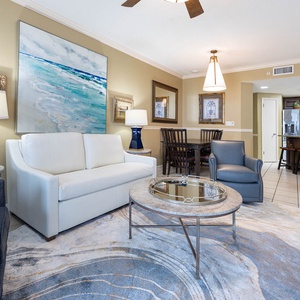 Stylish living area featuring a plush sofa with queen sleeper, elegant decor, and a view of the dining space and kitchen