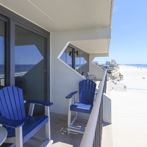 Relaxing beachfront views from this balcony featuring comfortable blue chairs, perfect for relaxation