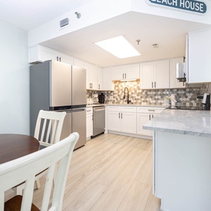 Bright kitchen featuring sleek cabinetry, a hexagonal backsplash, and a dining area with a wooden table and white chairs