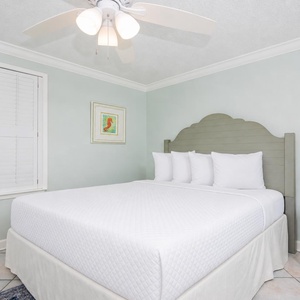 Serene guest bedroom featuring a plush queen bed, soft blue walls, and charming artwork, perfect for restful nights