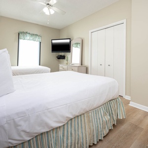 Relax in this inviting guest bedroom featuring two double beds, a wall-mounted TV, and soft lighting for a restful stay
