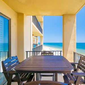 Enjoy a relaxing view from the balcony overlooking the beach, with a table and chairs inviting you to unwind