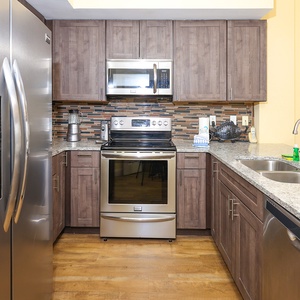 This kitchen features stainless appliances, granite countertops, and a stylish backsplash, perfect for meal preparation