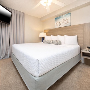 Rest peacefully in this inviting bedroom featuring a king bed, soft linens, and a mounted TV for entertainment