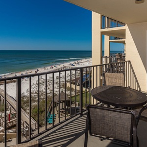 Enjoy breathtaking views from the balcony, featuring a cozy table and chairs overlooking the serene beach and sparkling waters