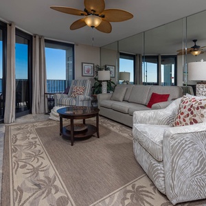 Cozy living area features a comfortable sofa with queen sleeper, accent chairs, and a view of the gulf through large windows