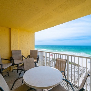 Enjoy stunning beachfront views from this cozy balcony, featuring a round table and comfortable seating for relaxation