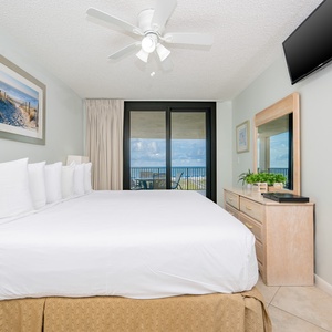 Master suite bedroom featuring a king bed, stylish decor, and easy access to the balcony with beautiful views