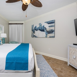 Master suite bedroom with a plush king bed, beach-themed decor, and a flat-screen TV for your entertainment