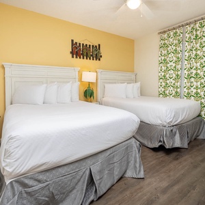 Relax in this cheerful guest bedroom featuring two comfortable double beds, vibrant decor, and a yellow accent wall