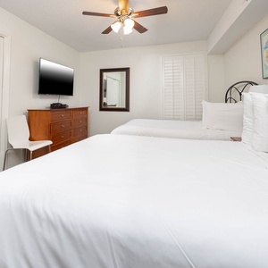 Relax in this guest bedroom featuring two comfortable double beds, a TV, and stylish decor for a relaxing stay