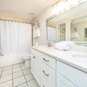 Refresh in this guest bathroom featuring a dual vanity, ample storage, and a relaxing tub-shower