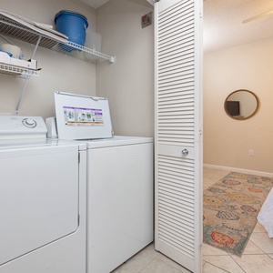 Laundry area features a washer and dryer with shelving above, leading to a cozy guest bedroom with a decorative rug