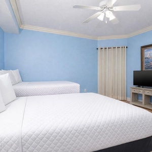 Cozy guest bedroom featuring a full and a twin bed, a TV, and soft blue walls for a relaxing atmosphere