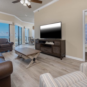 The inviting living area features a large TV, comfortable seating, and expansive windows showcasing a beautiful beach view