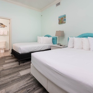 Two double beds with turquoise headboards, creating a refreshing and inviting guest room atmosphere