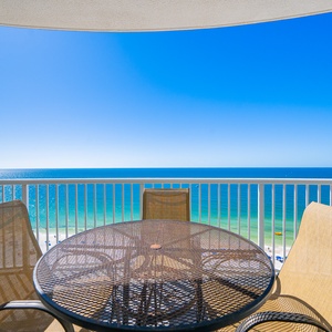 Metal table on the balcony invites you to savor sparkling blue waters and sky from this serene spot