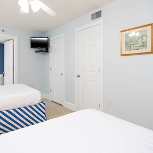 Cheerful guest bedroom featuring double beds, a TV, and coastal decor that enhances your beach getaway