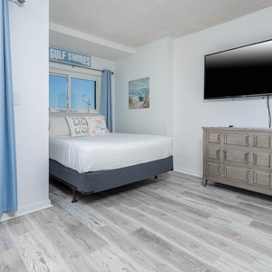 This studio suite features a comfortable bed, a large TV, and a stunning beach view through sliding glass doors