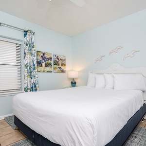 Brightly decorated bedroom featuring a queen bed, colorful curtains, and art, creating a cheerful and relaxing atmosphere