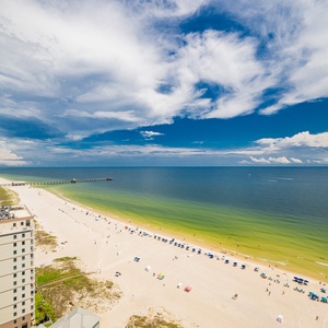 Take in the expansive views of the shoreline and vibrant beach umbrellas from your inviting balcony