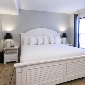 King suite featuring a plush bed, stylish decor, and a serene coastal-themed artwork
