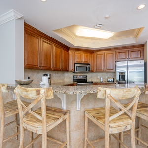 Inviting kitchen with granite countertops, stainless appliances, and rustic wooden bar stools for casual dining