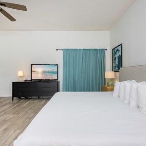 Spacious guest bedroom featuring a cozy king bed, two twin bunk beds, and a TV for relaxing evenings