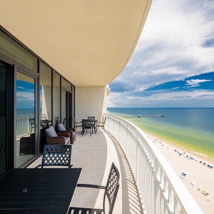 Relax on the spacious balcony with comfortable seating, enjoying breathtaking views of the coastline and pier