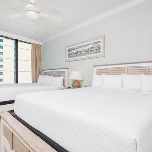 Bright guest bedroom featuring two comfortable queen beds and large windows showcasing beautiful views