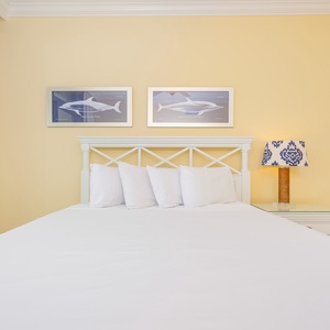 Inviting guest bedroom featuring a queen bed, cheerful yellow walls, and charming nautical artwork