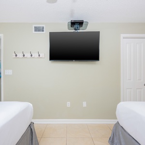 Brightly colored artwork adorns the hall, while a mounted TV is positioned above two comfortable queen beds with crisp linens