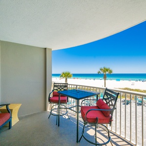Relax on the balcony with cozy seating and enjoy the impressive view of the beach and pool area below