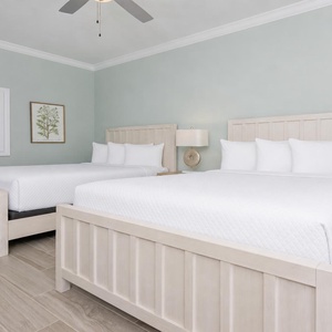 Inviting guest room featuring two queen beds with soft linens, stylish decor, and a soothing vibe