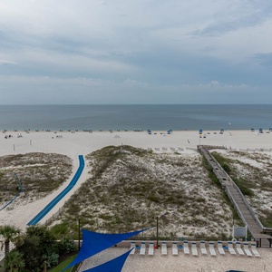 Experience the serene view of the beach with lounge chairs and umbrellas, perfect for enjoying the sun and surf