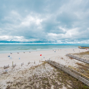 This bright and sunny beachfront view showcases soft white sands and gentle waves, perfect for a relaxing getaway