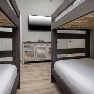 Twin bunk beds frame a cozy guest room featuring a TV and dresser, perfect for family or friends enjoying a beach getaway