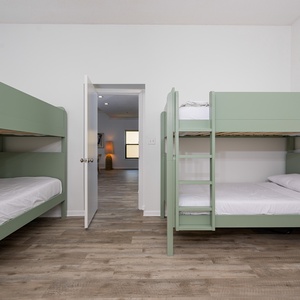 Guest room featuring two stylish green bunk beds, a king bed, and a cozy atmosphere, perfect for family getaways