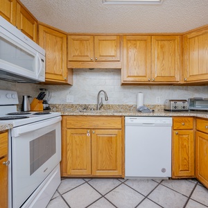 Bright granite counters complement warm oak cabinets as you prepare beachside meals in the kitchen