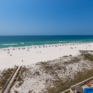 Enjoy a serene beachfront view with gentle waves lapping against the shore and a glimpse of the inviting pool area below