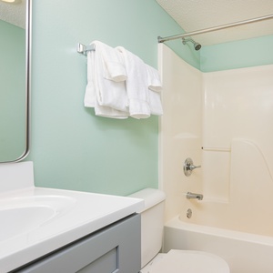 Towels await after refreshing showers in the bathroom with soft mint walls and a tub shower combo