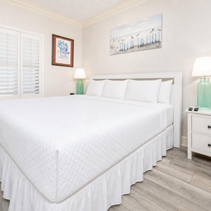 White linens and soft lamps create a peaceful setting in the guest suite with a king bed