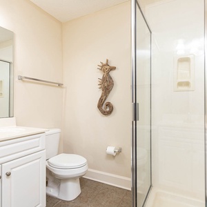 Refresh in the guest bathroom featuring a glass walk-in shower, sleek vanity, and decorative seahorse accent