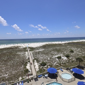Stunning view of the beach and turquoise gulf waters, featuring a path leading to the shore and a pool area below